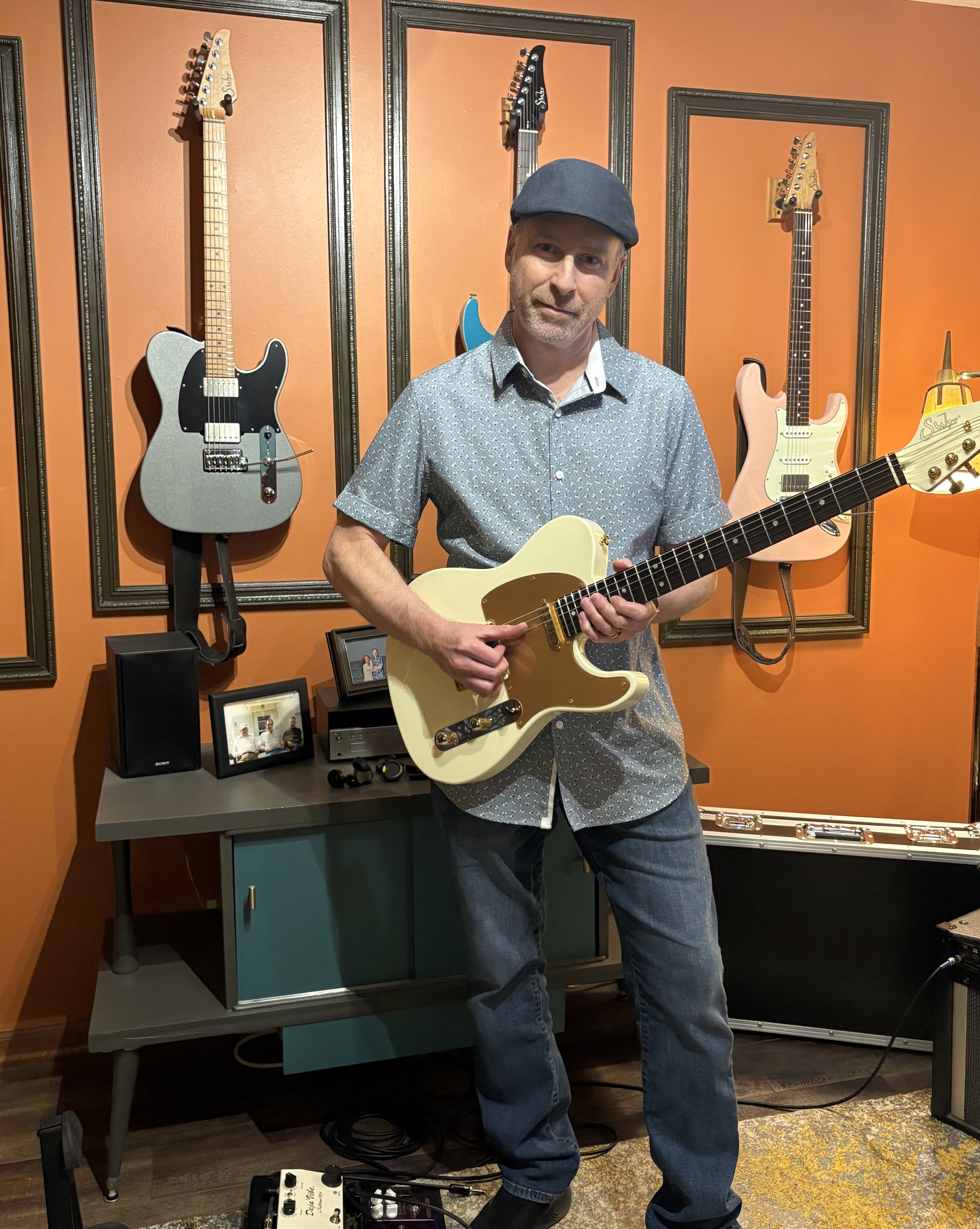 Erik Davis with a cream Telecaster in front of his studio guitar wall