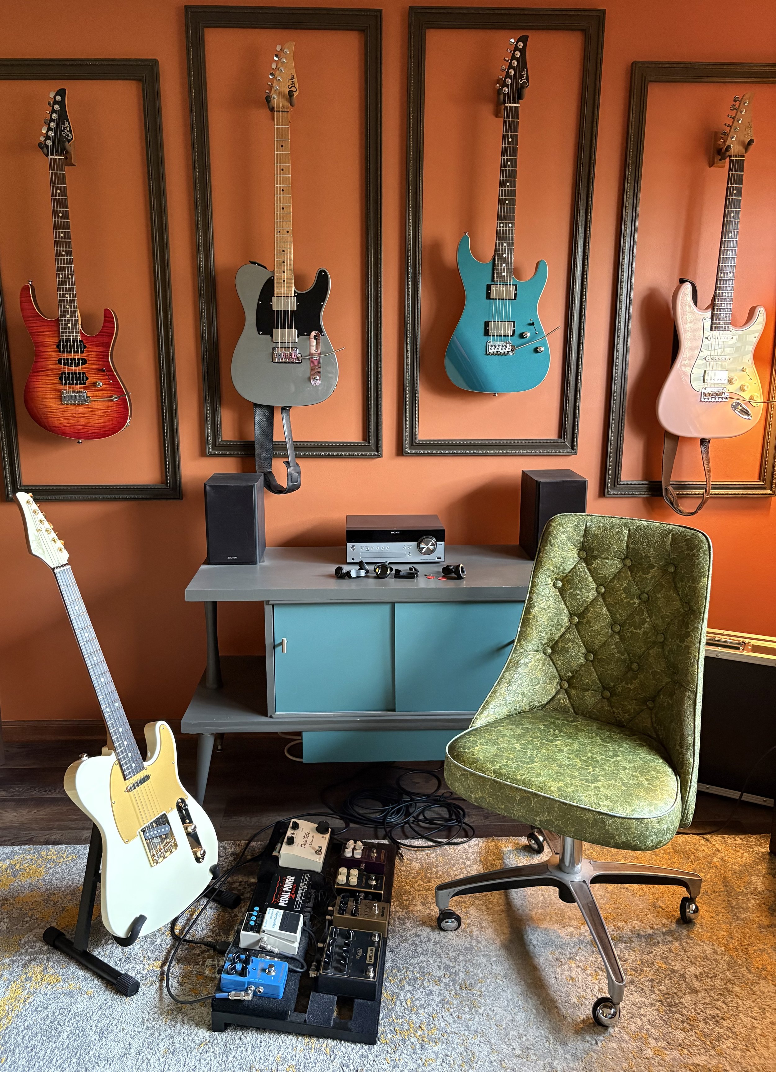 Guitar wall with turquoise credenza and olive-green vinyl chair